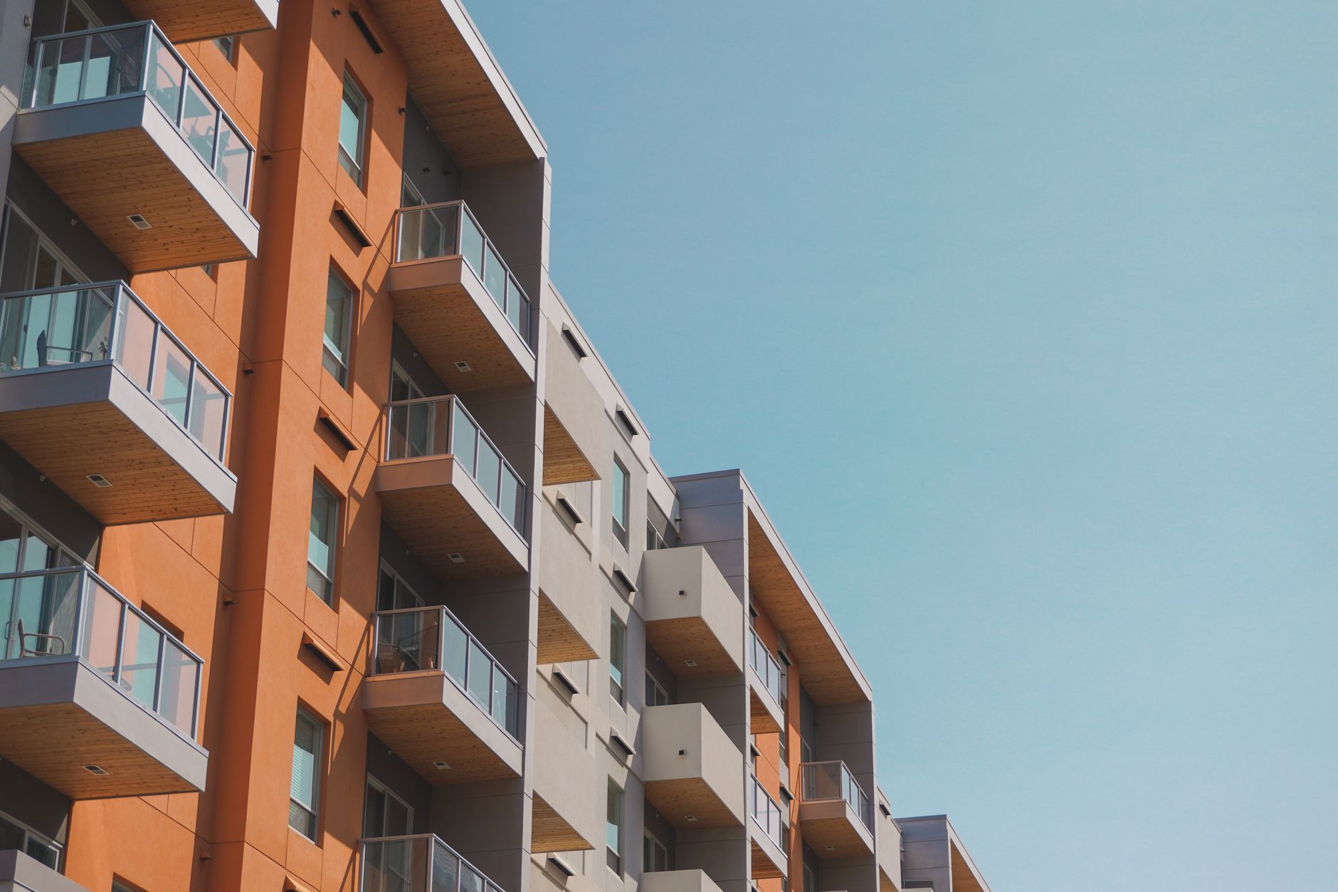 A contemporary apartment building with glass balconies under a clear blue sky