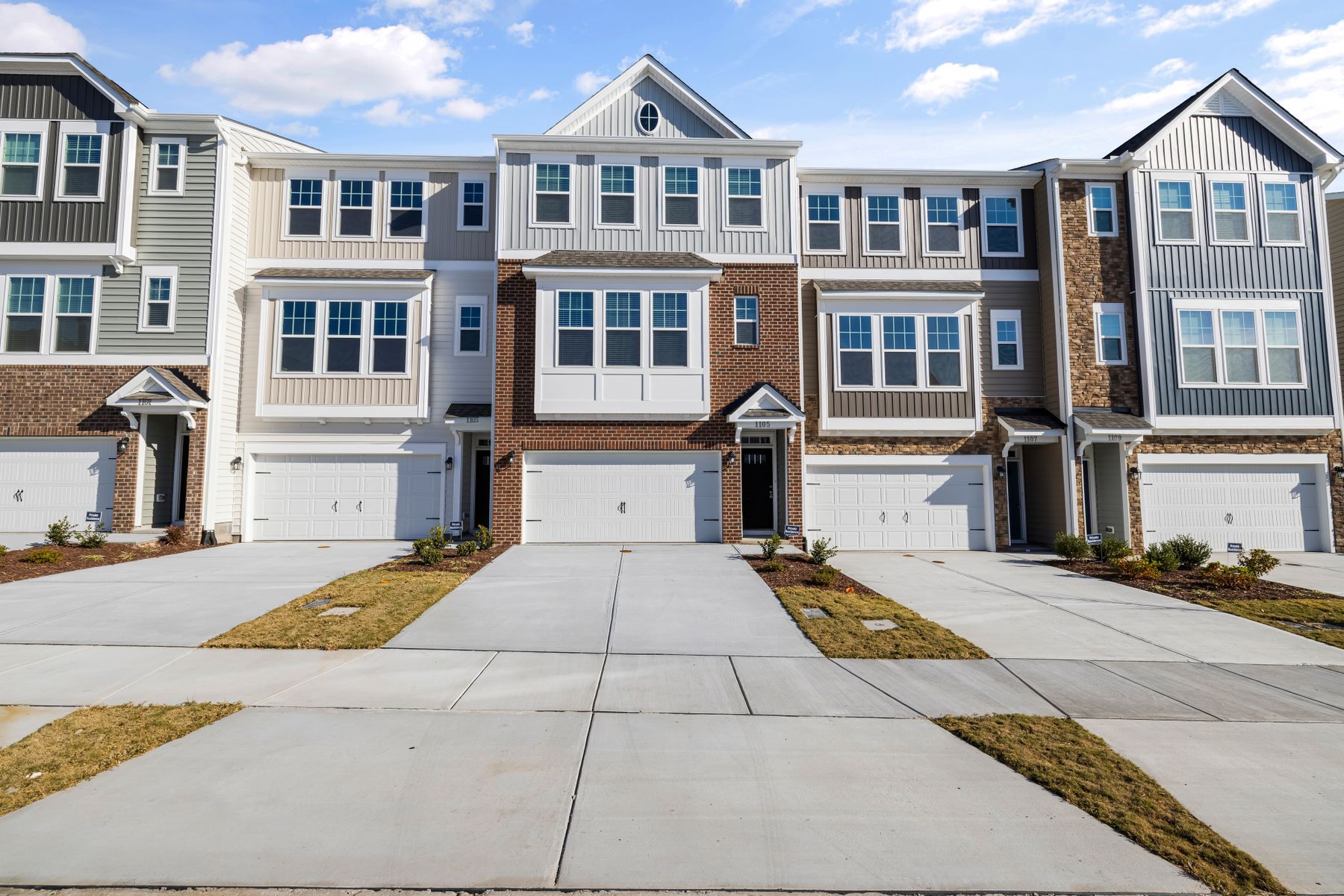 Row of modern townhouses with attached garages under a clear blue sky