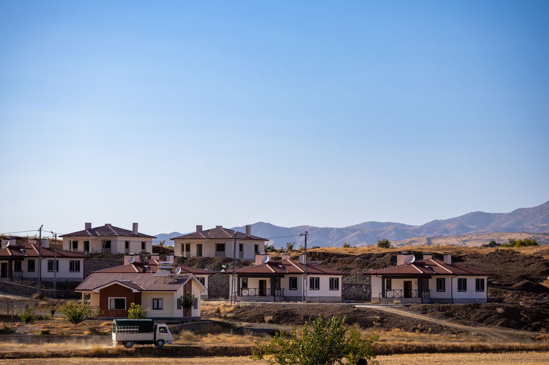 Rows of newly built homes on rising ground with mountains in the distance